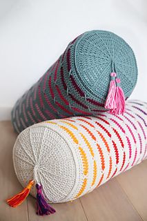 two round crocheted pillows with tassels on the ends, one in multicolored yarn