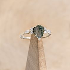 a close up of a ring on top of a piece of wood with diamonds around it