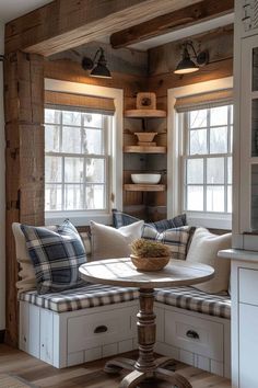 a table with some pillows on top of it in front of two windows and a window seat