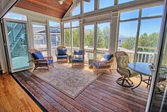 a sun room with wooden floors and lots of glass doors leading to the deck area