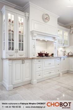 a kitchen with white cabinets and marble counter tops in an open floor plan, along with a clock on the wall