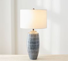 a table lamp sitting on top of a wooden table next to a white light bulb