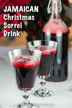 two glasses filled with red liquid sitting on top of a table next to a bottle