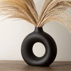 a black vase with some dry grass in it