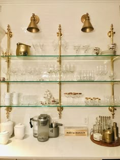 the shelves are filled with glassware and gold trimmings, including an espresso machine