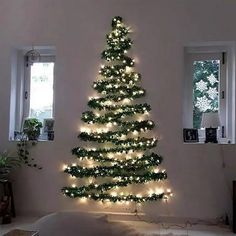 a christmas tree is lit up in the corner of a room with windows and lights