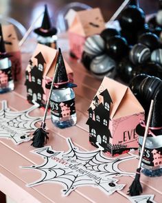 some little houses that are sitting on a table with black and pink decorations around them