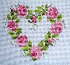 a cross stitch heart with pink roses and green leaves