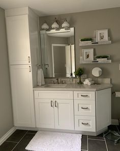 a bathroom with white cabinets and gray tile flooring