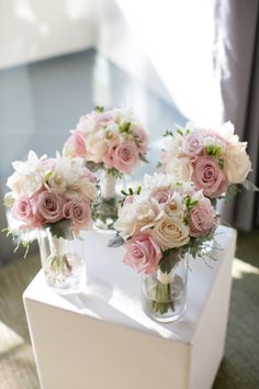 four vases filled with pink and white flowers on top of a table next to a window