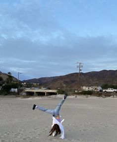 a person doing a handstand on the beach