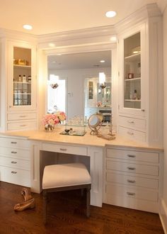 a bathroom with white cabinets and wooden flooring next to a counter top area that has a stool on it