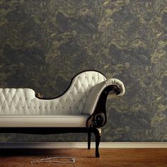 a white couch sitting on top of a wooden floor in front of a wall covered in marble