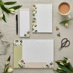 two notebooks with flowers on them next to a cup of coffee and some scissors