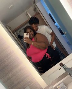 a man and woman taking a selfie in a bathroom mirror with their cell phone