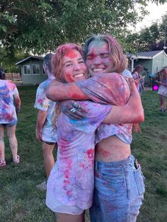 two girls hugging each other in the middle of a group of people covered in colored paint