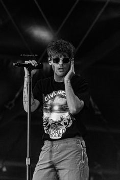 a man standing on top of a stage holding a microphone in front of his face