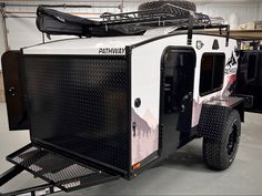 a white and black trailer with luggage strapped to it's back end in a garage