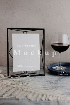 a glass of red wine next to a sign that says mock up on the table