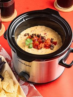 a crock pot with tortilla chips and salsa in it on a table