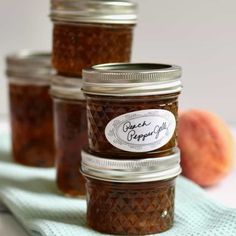 four jars filled with jam sitting on top of a blue towel next to an orange