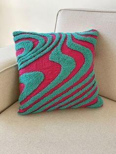 a pink and green pillow sitting on top of a couch