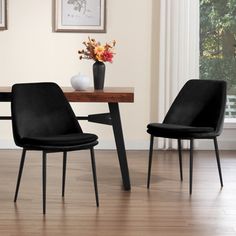 two black chairs sitting at a table in front of a vase with flowers on it