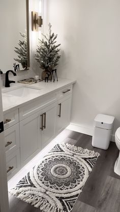 a bathroom with a white toilet sitting next to a sink and a christmas tree on the counter