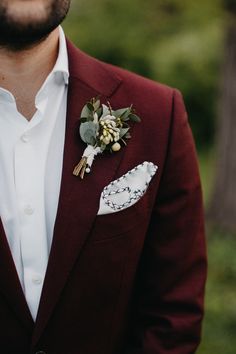 a man in a red suit with a boutonniere on his lapel