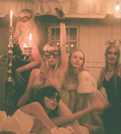 four women dressed up in costume posing for the camera with candles on their heads and hands