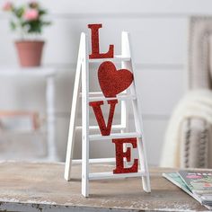 This heartwarming Valentines Day decoration makes a great gift for your valentineor keep it for your own home dcor! Featuring a white ladder with glittery red letters spelling out the word Love, this decoration can be displayed on your coffee table, mantle or desk to spread a little love all around. Includes metal hinge. Wood. 4 1/2" x 6 1/2" x 12" Size: 4-1/2" x 6-1/2" x 12".  Color: Multicolor. Valentines Desk Decorations Offices, Valentines Decor Bedroom, Valentines Crafts Dollar Tree, April Decorating Ideas, Valentines Day Outdoor Decorations, Valentine Office Decor Work Spaces, Valentines Fireplace Decorations, Valentine Display Ideas Retail, Valentine’s Day Tree Ideas