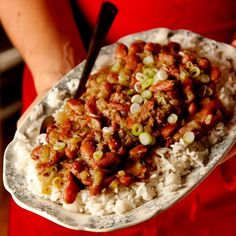 a person holding a plate full of rice and beans with chopsticks in it