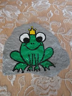 a green frog with a crown on it's head sitting on top of a rock