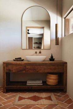 a bathroom sink sitting under a mirror next to a wooden counter top with a bowl on it