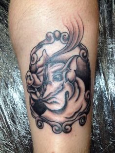 a black and white tattoo on the leg of a man with a cat head in it