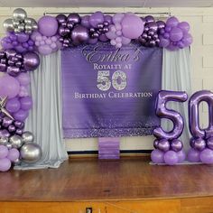 purple and silver balloons are set up on the stage for a 50th birthday celebration with 50