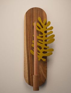 a wooden object with a candle on top of it and a leaf decoration above it