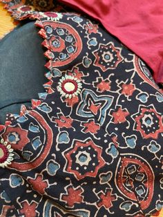 A beautiful hand block printed (Ajrakh) pure cotton blouse in sizes 40 and 42 with hand embroidered mirror (authentic mirror- not mica) with elbow sleeves. The body has the ajrakh print in a black base while the sleeves are in contrast - dark maroon. Blouse is padded with hook in the back. Front and back both are U shaped neckline. Extra margin available to increase up to one size. You may reach out to us for alterations. Size change is a $5 extra charge. Note: We try to stay as accurate to the Ajrak Blouse, Red Cotton Block Print Blouse, Festive Cotton Bandhani Print Blouse Piece, Festive Cotton Bandhani Blouse Piece, Cotton Bandhani Print Blouse For Navratri, Cotton Blouse Piece With Bandhani Print For Navratri, Cotton Bandhani Blouse Piece For Navratri, Red Block Print Cotton Blouse Piece, Red Cotton Block Print Blouse Piece