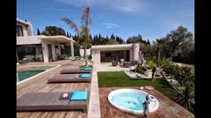 a hot tub sitting on top of a wooden deck next to a swimming pool in front of a house