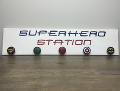 there is a sign that says superhero station on the wall next to some balls and a bat