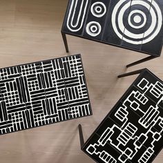 three tables with black and white designs on them sitting on top of a wooden floor