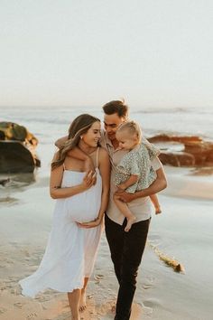 a man and woman holding their baby on the beach