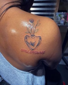 the back of a woman's shoulder with a tattoo on it that says still growing