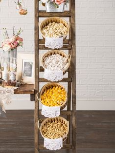 a wooden stand with baskets filled with popcorn and other snacks on it, along with flowers