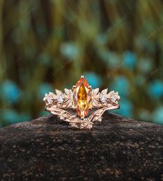 an orange and white diamond ring sitting on top of a rock