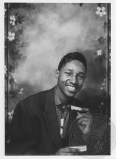 a black and white photo of a young man holding a plaque in front of him