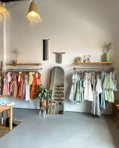 a room filled with lots of clothes hanging from the ceiling and shelves on the wall