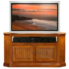 an entertainment center with a flat screen tv on it's side and the ocean in the background