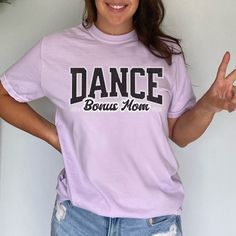 "Dance Bonus Mom Tee, Proud & Loud Dance Bonus Mom Gear, Step Mom Gift, Comp Dance Bonus Mom Tee, Trendy Dance Step Mom Comfort Colors Tshirt How To Order - Please make sure you have looked at all sizes and color charts. - Select from the various T-Shirt sizes and colors from scroll down menus. - Fill in the personalization box (if provided) as exemplified. - Click \"Add to cart\" button. You can turn back and add more items of different size and color. Order Process - Our processing time is 5-10 days. - Shipping is first class, usually 1-5 business days (after processing time) depending on the location. - You can choose faster shipping options at checkout. (This does not affect the production time, production time remains the same, expedited shipping is only for delivery time that will be Purple Graphic Print Hip Hop Tops, Purple Cotton Hip Hop Tops, Short Sleeve Tops With Graphic Print For Dance Class, Cotton Short Sleeve Tops For Dance Class, Short Sleeve Shirt With Letter Print For Dance Class, Hip Hop Graphic Print Tops For Dance, Hip Hop Dance Tops With Graphic Print, Hip Hop Crew Neck Top For Dance, Hip Hop Purple Top With Letter Print