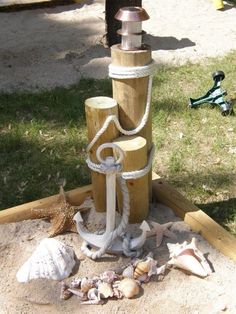 an anchor, rope and seashells are on the sand